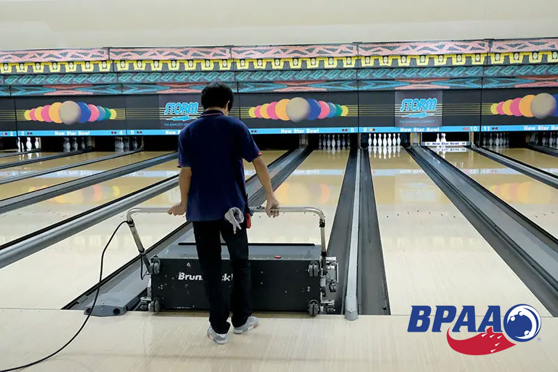 bowling alley employee cleaning lanes